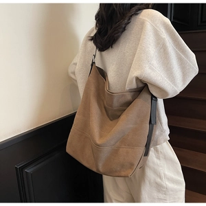 Close-up of large brown canvas tote bag featuring adjustable strap and buckle details