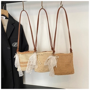 Détail de sacs bandoulière en paille tressée avec breloques en dentelle et perles