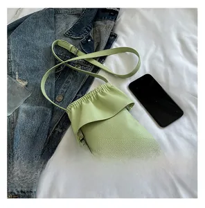 Détail du sac à téléphone vert clair avec texture litchi, bords froissés et bandoulière