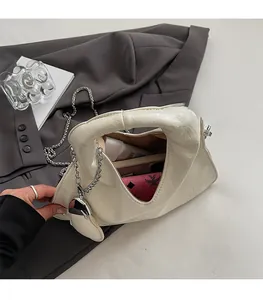 Detail view of cream handbag with wrinkled texture and heart charm showing interior capacity