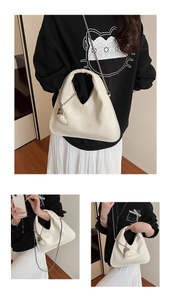 Detail of off-white hobo bag with embossed texture, chain strap and heart charm