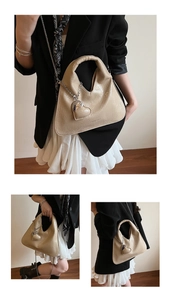Detail of beige shoulder bag with unique wrinkled texture and silver heart pendant