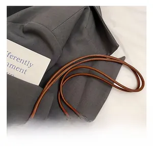 Détail d'un sac bandoulière tissé avec fine lanière en cuir et nœud en perles