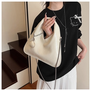Detail view of cream hobo bag with pleated leather texture and a fine metal chain strap