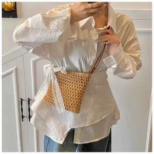 Détail du sac bandoulière en paille avec nœud en dentelle blanche et sangle en cuir