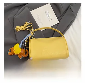 Detail of yellow pebbled leather barrel bag featuring a cute elephant charm on a blazer