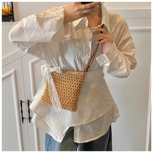 Détail du sac bandoulière en paille tissée avec grand nœud en dentelle blanche de plage
