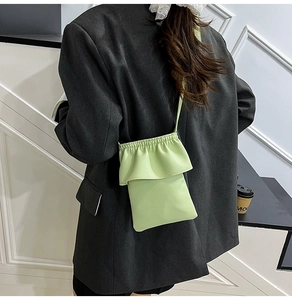 Détail du petit sac bandoulière vert pour téléphone avec bords plissés porté par un mannequin