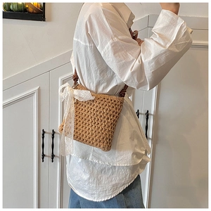 Détail du sac bandoulière en paille avec un grand nœud en dentelle blanche et sangle