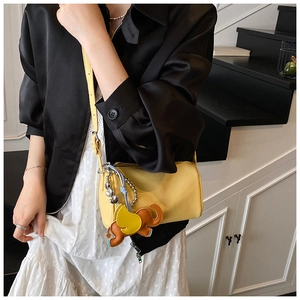 Crossbody view of yellow litchi pattern leather cylinder bag with cute elephant charm