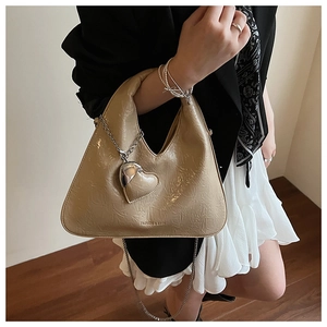 Beige pleated crossbody dumpling bag with heart charm and chain strap shown on model