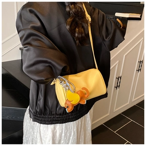 Chic yellow textured leather shoulder bag with a colorful elephant charm on a model