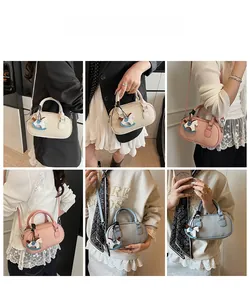 Mini borsa Boston con trama a litchi mostrata a mano e a tracolla sulla modella