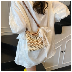Détail du sac tressé beige avec un nœud en dentelle blanche et bandoulière en cuir