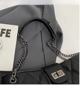 Vue détaillée de la texture en cuir noir matelassé et du fermoir sur le sac à bandoulière