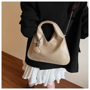 Detail of beige pleated leather moon bag with heart charm and silver metal chain strap