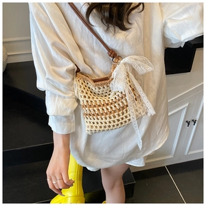 Détail d'un sac bandoulière tissé avec nœud en dentelle blanche et bandoulière en cuir brun