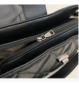 Gros plan d'une fermeture éclair en métal argenté sur un sac fourre-tout en cuir matelassé