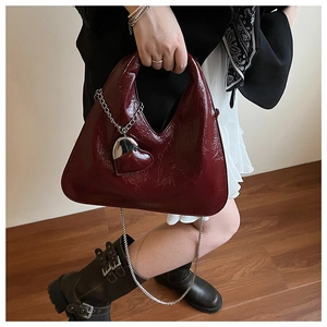 Detail of burgundy PU leather handbag with heart charm and silver chain strap