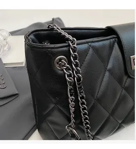 Gros plan sur la texture en cuir noir matelassé et la chaîne en métal du sac