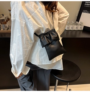 Petit sac bandoulière vertical noir avec détails volantés et texture cuir grainé