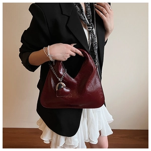 Detail of burgundy glossy patent leather dumpling bag with heart chain charm