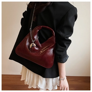 Close-up of wine red patent leather hobo bag with silver chain and heart pendant
