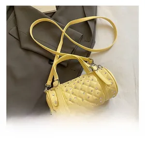 Détail macro du sac cylindre jaune avec matelassage en losange et clous en strass argentés