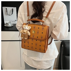 Détail du sac à dos marron avec motif imprimé et pendentif ours en peluche