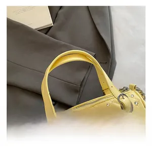Détail des poignées d'un sac matelassé jaune avec des rivets argentés élégants