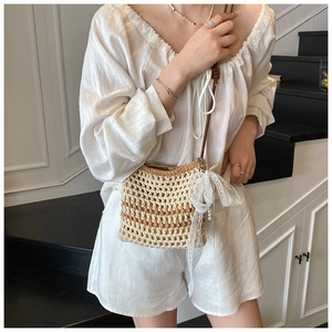 Détail du sac bandoulière en paille tressée avec nœud en dentelle blanche et perle