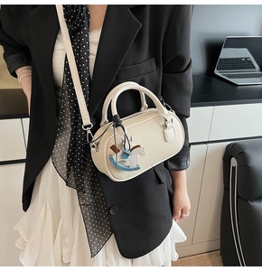 Dettaglio borsa boston in pelle litchi bianco crema con ciondolo a forma di cavallo