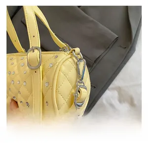 Détails du sac cylindrique matelassé jaune avec rivets en cristal et mousquetons argentés