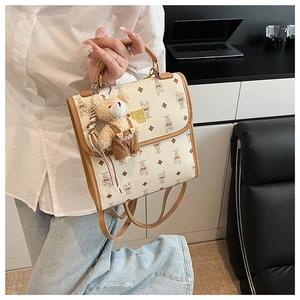 Détail du sac à main beige imprimé avec garniture en cuir et accessoire ours peluche