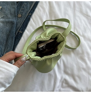 Détail d'un mini sac à bandoulière vert menthe en cuir grainé avec cordon de serrage