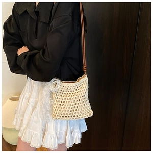 Détail du sac de téléphone en paille tressée avec nœud en dentelle et accents de perles