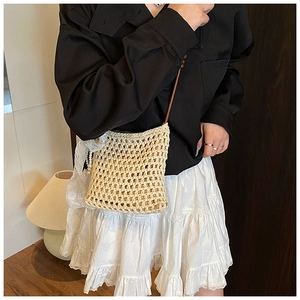 Détail du sac bandoulière tissé avec nœud en dentelle blanche et pendentif perle élégant