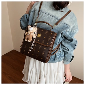 Sac à dos vintage marron avec motif monogramme et charm ours en peluche sur modèle