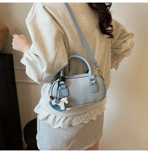 Detail of light blue bowling bag with lychee texture and a cute rocking horse charm