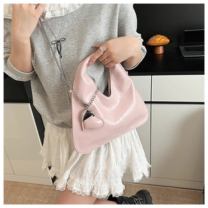 Detail of pink glossy pleated triangle bag with silver heart charm and chain link handle