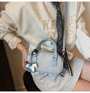 Detail of light blue lychee pattern bowling bag with cute rocking horse charm accessory