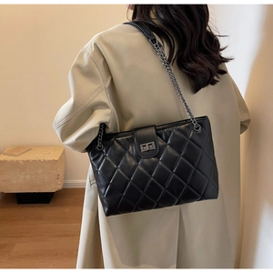 Détail du sac à bandoulière matelassé noir avec chaîne en argent et fermoir tournant