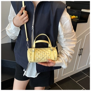 Détail du sac cylindrique jaune matelassé avec clous et ferrures argentées