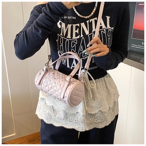 Détail du sac cylindrique matelassé rose avec cristaux porté par un mannequin