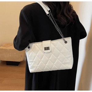 Détail du sac matelassé blanc avec chaîne et fermoir rotatif argenté porté à l'épaule