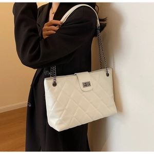 Dettaglio dell'elegante motivo trapuntato e della catena argentata sulla borsa tote bianca