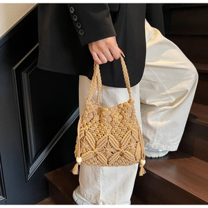 Détail d'un sac seau beige tissé main avec motifs floraux 3D et glands en perles de bois