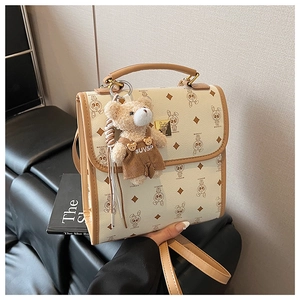 Détail du sac à dos imprimé crème avec bordure en cuir marron et pendentif ours en peluche