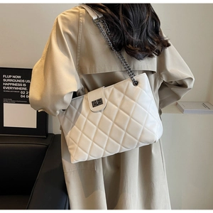 Vue détaillée d'un sac bandoulière blanc matelassé avec chaîne en métal porté par un modèle