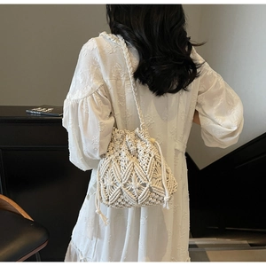 Vue arrière d'un sac seau en paille tressée crème au design minimaliste avec cordon de serrage